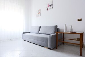A modern living room with a grey sofa, a wooden side table, and two abstract wall art pieces.