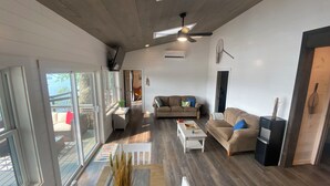 Un salon spacieux doté d’un haut plafond, d’un ventilateur de plafond et d’une grande fenêtre laissant entrer la lumière naturelle.