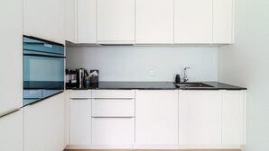 Une cuisine moderne avec des armoires blanches, un plan de travail noir et un four en acier inoxydable.