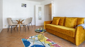 A living room with a sofa, chairs, a glass table, and a chandelier. - Appartement Herta - Welkeys (Biarritz)