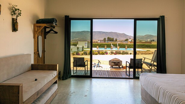 Un dormitori amb un gran finestral corredís que dona a una zona exterior amb piscina i seients.