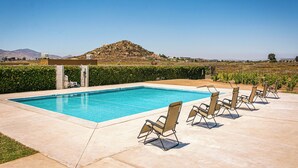 Una piscina amb gandules i vista a un turó al fons.