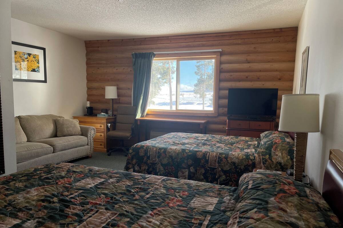 A cozy room with two beds, a desk, a chair, and a television.