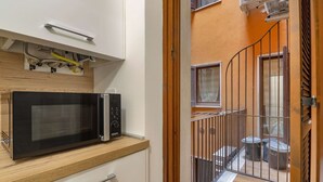 Eine kleine Küche mit Mikrowelle, Holz Arbeitsplatte und kleinem Fenster.