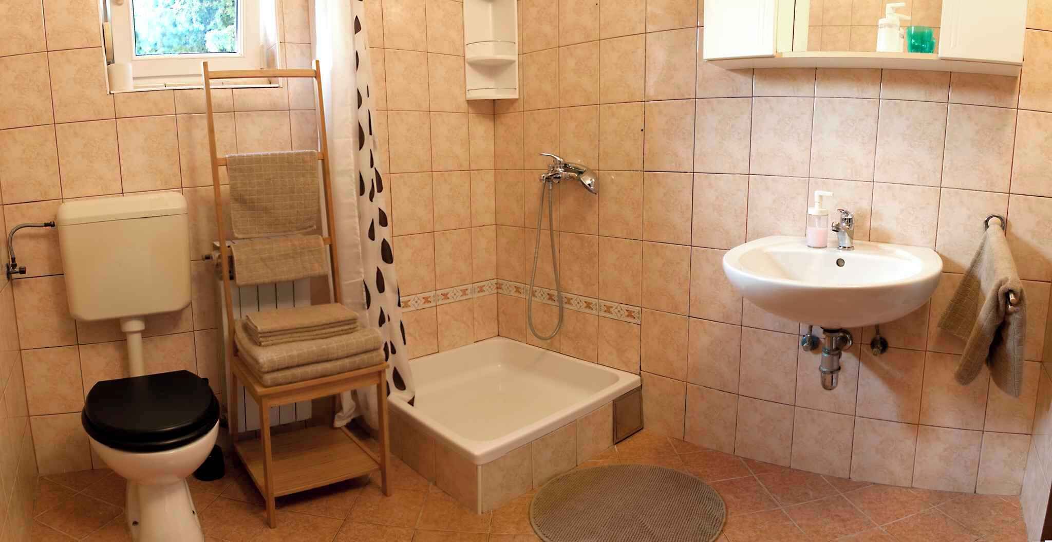 A small bathroom with a toilet, a shower, a sink, and a towel rack.