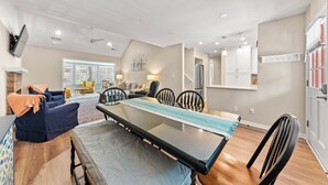 A spacious living room with a large glass-top dining table, comfortable seating, and a view to the outside.