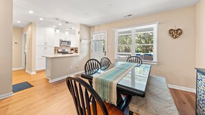 A dining area with a glass-top table, black chairs, and a striped table runner.