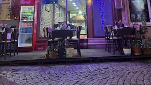 A hotel entrance with a neon sign, outdoor seating, and a Coca-Cola vending machine. - Yed Hotel (Istanbul)