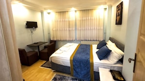 A hotel room with a bed, bedside tables, a desk, a chair, and a television mounted on the wall. - Yed Hotel (Istanbul)