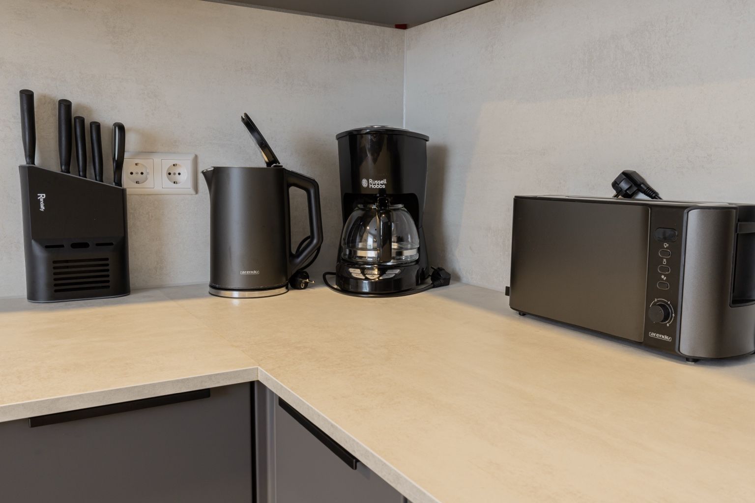 Eine Küche mit Kaffeemaschine, Toaster und einem Messerblock auf der Arbeitsfläche.