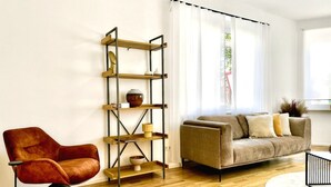 A modern living room with a sofa, a red armchair, a wooden floor, and a bookshelf. - Spacious Design Retreat for Groups & Families (Stuttgart)