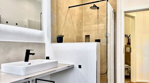 A modern bathroom with a white sink, a handheld showerhead, and a mirror. - LaMiaCasa Stuttgart-Ost | 145 sqm | 3 Bedrooms | 2 Baths | Parking (Stuttgart)