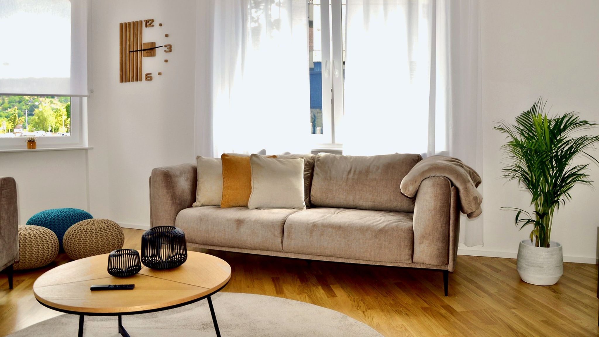 Ein Wohnzimmer mit einem beigen Sofa, einem runden Couchtisch und einer Topfpflanze.