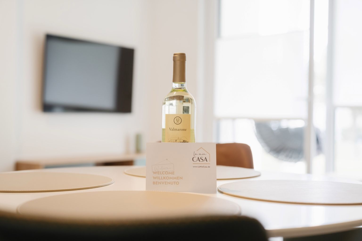 A bottle of Valmarnone wine on a table with a welcome sign for La Mia Casa.