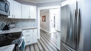 A modern kitchen with white cabinets, a stainless steel refrigerator, a built-in oven, and a tiled backsplash. - Beautiful Victorian Home (Tacoma)