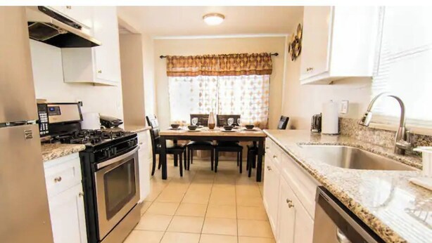 Een praktische keuken met een gasfornuis, oven en een eethoek met een tafel en stoelen.