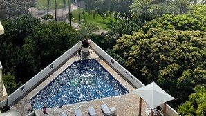 A rooftop pool with lounge chairs and a view of a cityscape with high-rise buildings.
