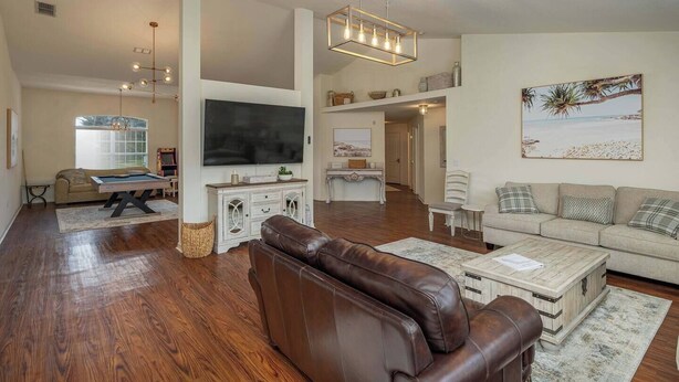 A spacious living room with a pool table, a leather sofa, and a flat-screen TV mounted on the wall. - Large House, Fireside Hot Tub, King Bed Suite (lakeland)