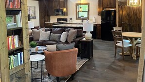 A cozy living room with a fireplace, a dining area, and a kitchen. - Whippoorwill Run Cabin — Jasper, AR (Jasper)