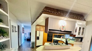 A modern kitchen with white cabinets, a central island, and a dining area with two chairs.