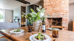 A dining table set with plates of food, a bottle of wine, and a large potted plant. - Key Cottage, Orford (Orford)