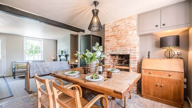 A dining area with a brick fireplace, wooden table, and chairs. - Key Cottage, Orford (Orford)
