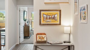 Un couloir orné d’une pancarte sur laquelle on peut lire « Bienvenue à tous », d’un cadre avec l’inscription « Salutations de l’Oklahoma » et d’une petite table sur laquelle sont posés une carte et une lampe.