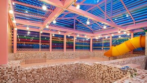 An indoor swimming pool with a colorful mosaic wall and a yellow slide. - JANGYU ALMOND KIDS HOTEL (Gimhae)
