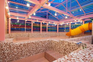 Una piscina interior con una pared de mosaicos coloridos y un tobogán amarillo.