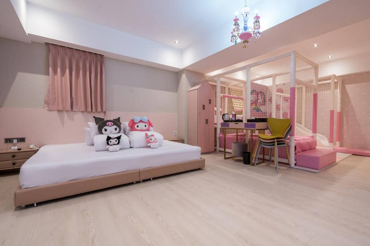 Een moderne slaapkamer met een groot bed, een bureau en een speelhoek met een glijbaan.