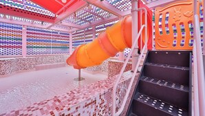 A water play area with a slide and steps, surrounded by colorful, patterned walls. - JANGYU ALMOND KIDS HOTEL (Gimhae)