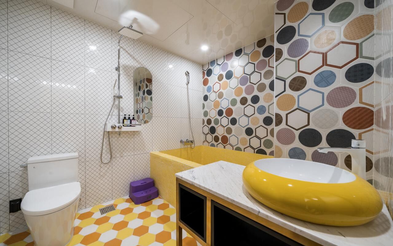 A bathroom with a white toilet, a yellow sink, and a shower.