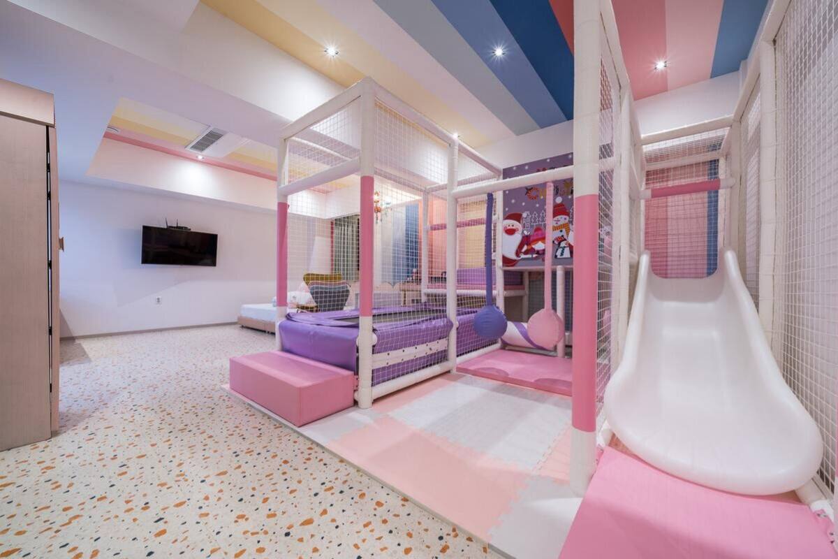 Een kinderspeelruimte met een glijbaan, zachte zitplaatsen en speelconstructies met netten.