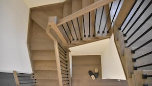 A wooden staircase with black handrails and a pair of slippers on the landing. - PARADISE VILLA 8 (Bowmanville)