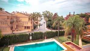 A residential area with a swimming pool, palm trees, and houses with balconies.