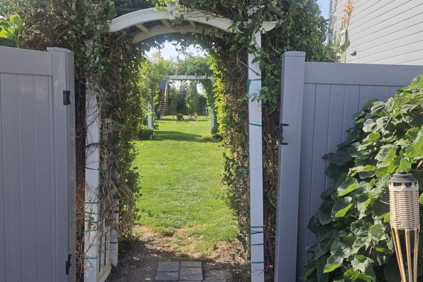 A gated entrance with a pathway leading to a grassy yard.