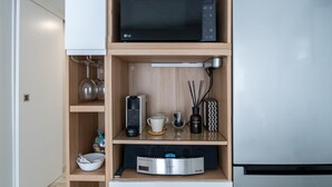 Una cocina moderna con microondas integrado, cafetera y tetera sobre la encimera.