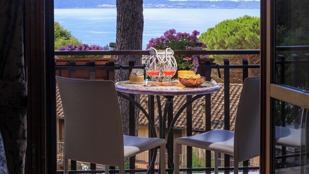 Un balcó amb dues cadires, una taula amb begudes i aperitius, i vista al mar.