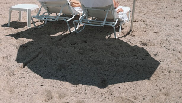 Two white beach chairs under a white umbrella with "BEACH HOUSE" written on it, positioned on a sandy beach with a clear sky and calm sea in the background. - Deluxe Studio with King size bed, Kitchenette and beach service at Bal Harbour. Beach service included (Bal Harbour)