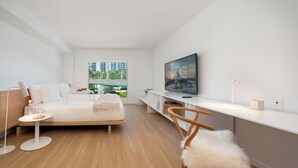 A modern bedroom with a bed, a TV, a desk, and a chair. - Deluxe Studio with King size bed, Kitchenette and beach service at Bal Harbour. Beach service included (Bal Harbour)