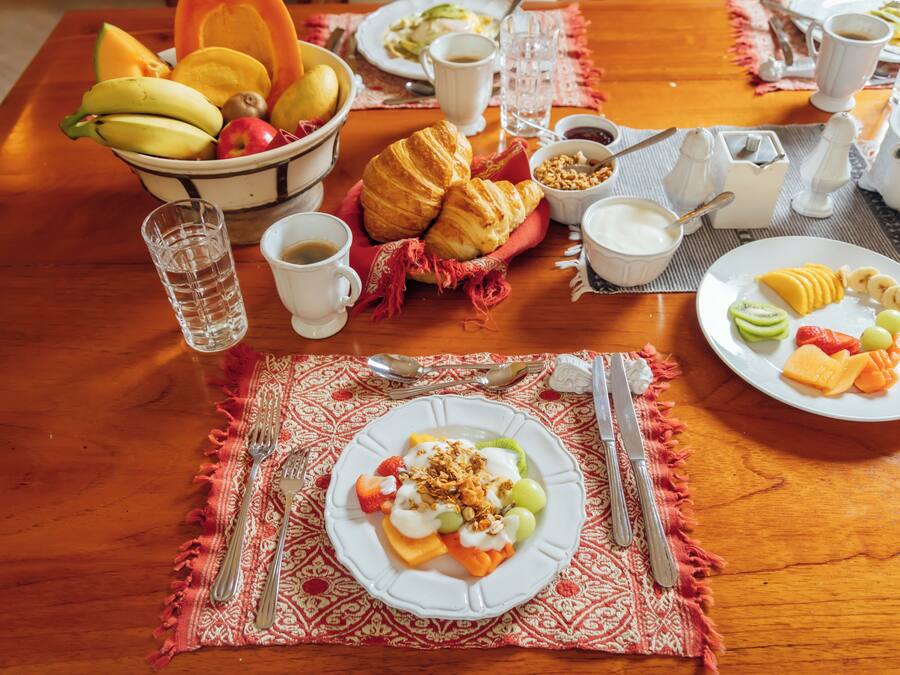 Ett frukostbord med croissanter, frukt och en tallrik med yoghurt och müsli.
