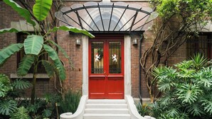 A brick building with a red door, white steps, and a glass awning. - Maison du comte (Mexico City)