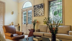 A living room with a brown leather armchair, beige sofa, and a coffee table with books and a vase. - Maison du comte (Mexico City)