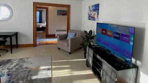 Ein Wohnzimmer mit Flachbildfernseher, Sofa, Couchtisch und Esstisch.