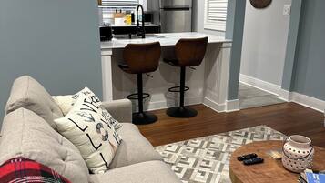 A living room with a sofa, a coffee table, and a kitchen in the background.
