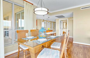 A dining area with a glass table, wooden chairs, and a blue lantern.
