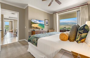 Een hotelkamer met een bed, een televisie, uitzicht op het strand en een balkon.