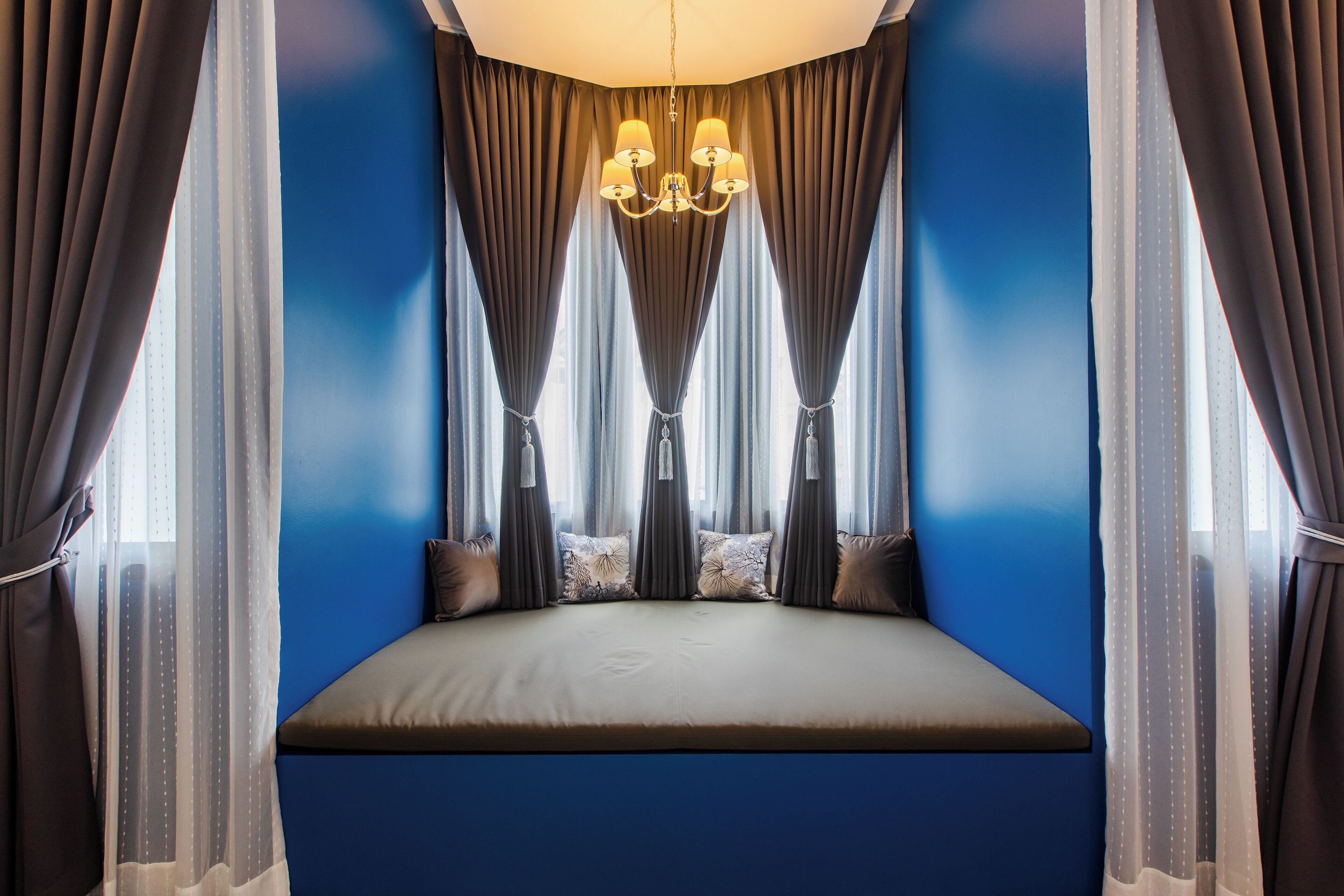 A bedroom with a bed, curtains, and a chandelier.
