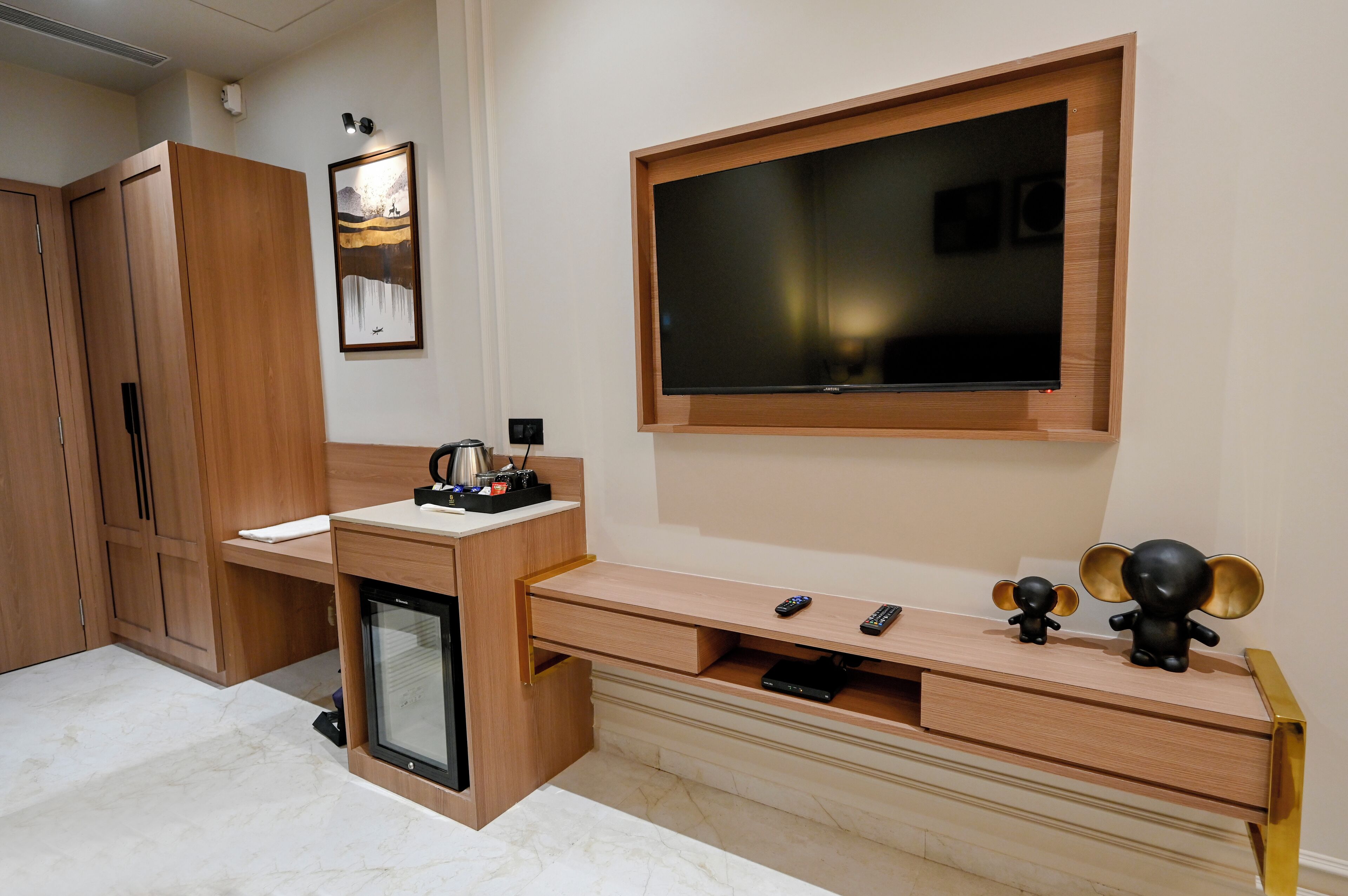 A modern living room with a TV mounted on the wall, a wooden cabinet, and a small refrigerator.