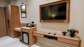 A modern living room with a TV mounted on the wall, a wooden cabinet, and a small refrigerator.